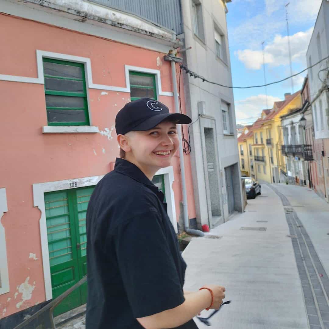 Personne dans une rue avec des maisons colorées, casquette.