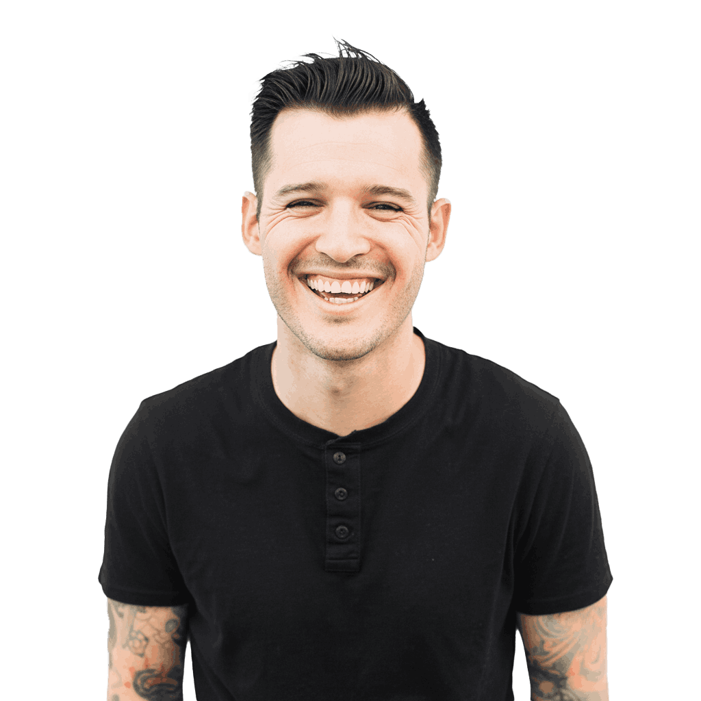 Homme de face très souriant avec T-shirt gris foncé et tatouages