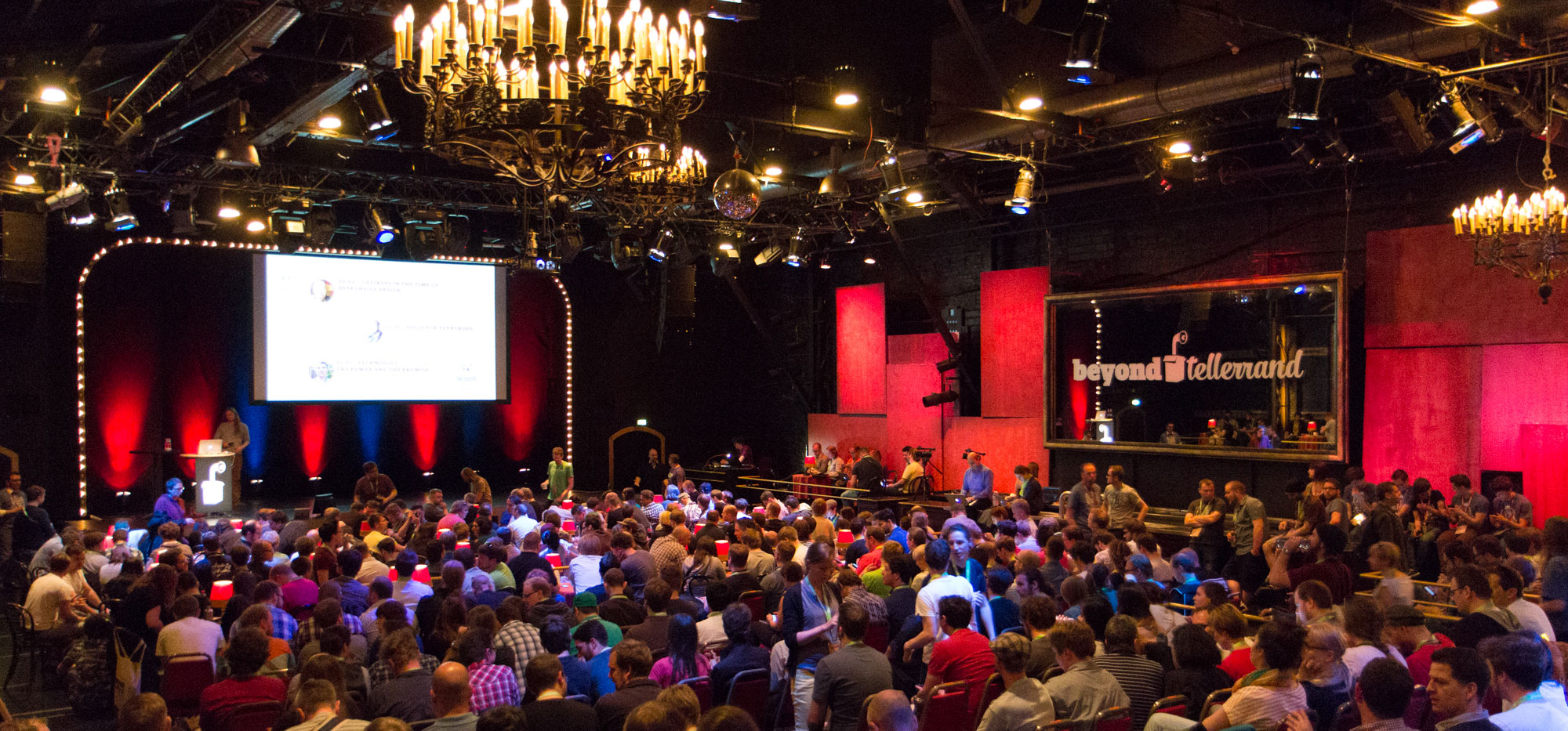 Salle de spectacle remplie de monde avec des murs rouge et un lustre chic